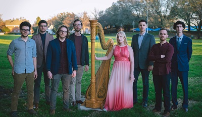 Anna Jalkeus and her ensemble standing in a grassy park-like setting