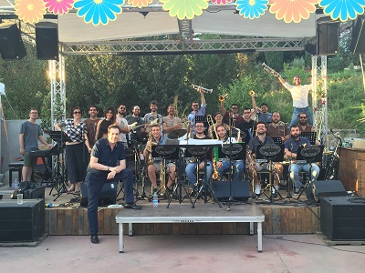 Rich DeRosa and the student big band he coached on an outdoor stage in Rome with trees behind it