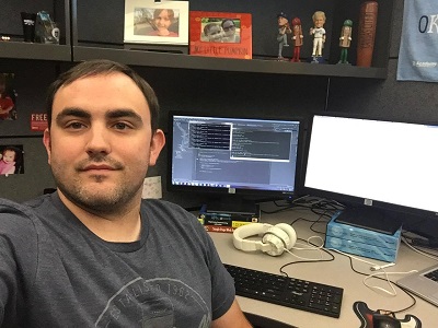 Shawn Strickland at his desk with code on the monitor